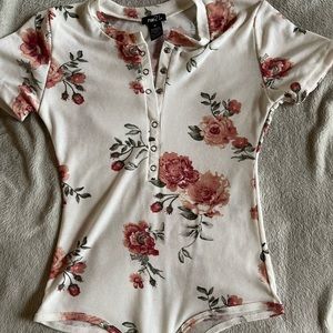 A rue 21 flower body suit in a medium . It is a bit sheer